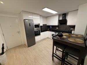 una cocina con armarios blancos y una mesa negra con sillas. en Apartamento Heliomar, en Málaga