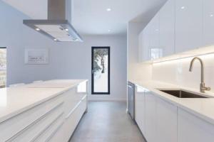 a white kitchen with white counters and a sink at Villa Boreale - Wellness and relaxation in Petite-Rivière-Saint-François