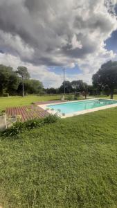 a swimming pool in the middle of a grass field at Cabañas del Valle in Huerta Grande