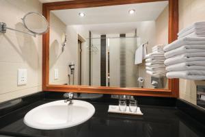 a bathroom with a sink and a mirror and towels at Ramada by Wyndham Bahrain in Manama