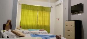 a room with a green curtain and a bed and a television at Hostal La GRAN Familia in Manta