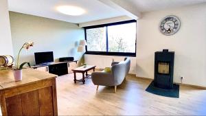 a living room with a chair and a clock on the wall at Villa le Menhir 4 Ch au Bord du Lac et Terrasse in Villefranche-de-Panat