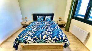 a bedroom with a bed with a blue and yellow blanket at Villa le Menhir 4 Ch au Bord du Lac et Terrasse in Villefranche-de-Panat