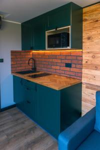 a kitchen with green cabinets and a brick wall at Balia pod lasem in Stara Łomnica +3 photos