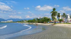 カラグアタトゥーバにあるPousada Sandramarのヤシの木と海と建物のあるビーチ