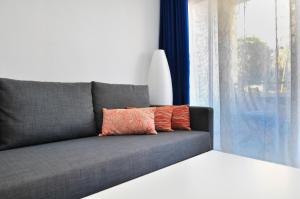 a gray couch with two pillows sitting next to a window at Prosurfing Apartamento in Playa del Ingles