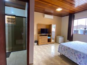 a bedroom with a bed and a tv and a window at Casa Morretes in Morretes