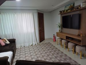 ボンビーニャスにあるCasa Bombinhas Com Piscinaのソファと薄型テレビのあるリビングルーム +12枚の写真