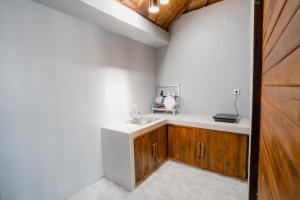 a kitchen with a sink and wooden cabinets at Akasea Guest House in Uluwatu