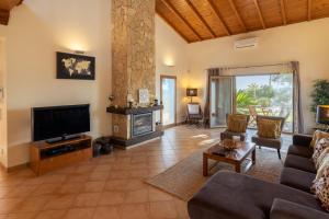 a living room with a couch and a television at Villa Monte Santo Estevão in Silves