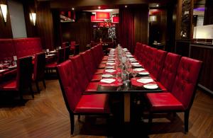 a long table in a restaurant with red chairs at Fantasyland Hotel in Edmonton