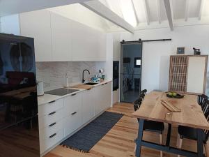 a kitchen with white cabinets and a wooden table at Our Place in Pico in Companhia de Cima