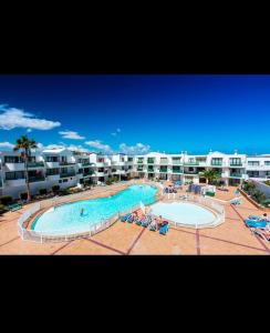 a large swimming pool in front of a apartment complex at La casita de Ohana in Costa Teguise