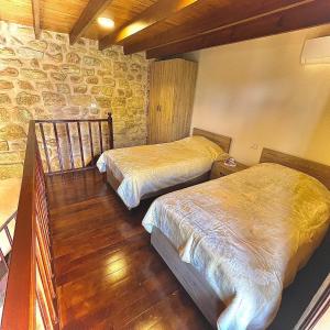 a bedroom with two beds and a stone wall at Batroun Old Town private duplex with garden in Batroûn