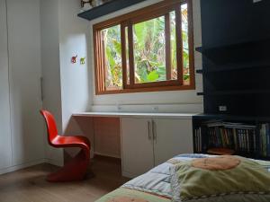 a bedroom with a window and a red chair at Casa Super Astral no Sul da Ilha in Florianópolis +37 photos