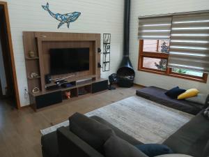 a living room with a couch and a flat screen tv at Casa Super Astral no Sul da Ilha in Florianópolis