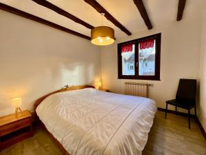 a bedroom with a white bed and a black chair at Le Grand Ours, appartement spacieux avec terrasse in Xonrupt-Longemer