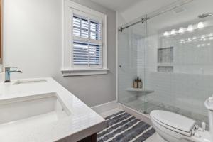 a white bathroom with a toilet and a glass shower at Charming Ann Arbor Retreat Near DT & Attractions home in Ann Arbor