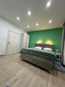 a bedroom with a green wall and a bed at Cibalae Residence, Self Check-In in Vinkovci