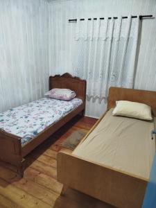 two beds sitting in a room with curtains at Quarto Privativo blue in Gramado