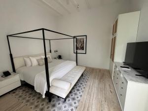 a bedroom with a large bed and a television at Casa Continental Hotel Boutique & Suites - Adults Only in Mérida