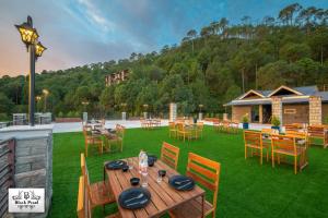 a patio with tables and chairs on a lawn at The Royals Luxury Apartments Rooftop Restaurant Lift Live Music Sat in Kasauli