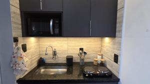 Una encimera de cocina con fregadero y microondas. en Loft Moderno e Aconchegante a Dois Passos da Feirinha do Alto!, en Teresópolis