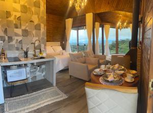 a living room with a bed and a table with food at Pousada Alto Colina - Chalé Siriema in Venda Nova do Imigrante