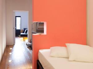 a bedroom with an orange wall and a bed at Casa Levante in Syracuse
