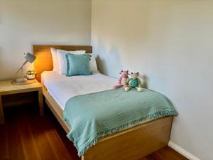 two stuffed animals sitting on a bed in a bedroom at Panda's Patch Dunsborough in Dunsborough