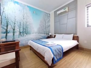 a bedroom with a bed and a painting of trees at Hotel Lê My in Can Tho