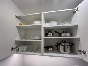 a white cabinet with dishes and pots and pans at Cologne City Studioaparment in Cologne