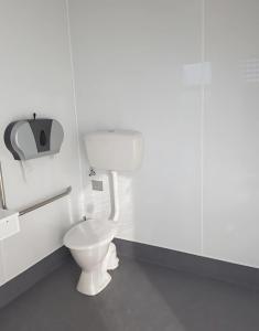 a white bathroom with a toilet and a paper dispenser at Urenui Beach Camp in Urenui +34 photos