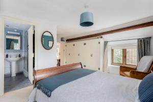 a bedroom with a bed and a sink and a mirror at Tom Callows - Gorgeous Rural Cottage in Epwell! in Epwell