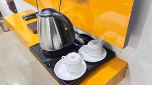 a coffee pot and two cups on a counter at Hotel Perfectionist- Free Airport Pickup in New Delhi