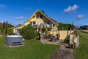 a yellow house with a hot tub in the yard at Ferienwohnung-Bergen in Wittenbeck