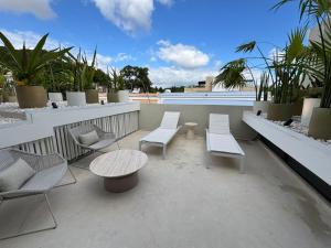 a patio with white chairs and tables on a balcony at Casa Continental Hotel Boutique & Suites - Adults Only in Mérida