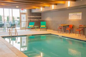 LogansportHome2 Suites By Hilton Logansport的酒店客房的游泳池配有桌椅