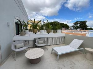 a balcony with two chairs and a table and some plants at Casa Continental Hotel Boutique & Suites - Adults Only in Mérida