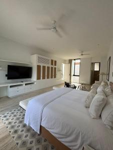a large white bedroom with a large bed and a flat screen tv at Casa Continental Hotel Boutique & Suites - Adults Only in Mérida