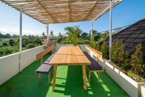 a wooden table on a balcony with benches at Villa Sound Canggu in Mengwi