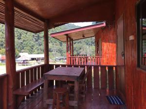 a wooden porch with a wooden table and stools on it at Mukakee in Ban Sop Mae Klang