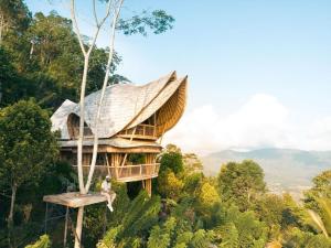 a tree house with a person sitting on a swing at Laputa Bali in Sidemen