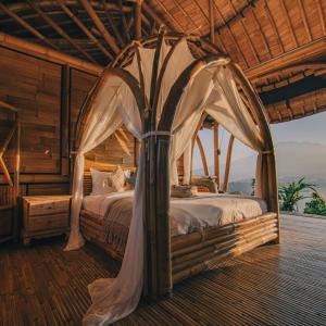 a bedroom with a bed with a canopy at Laputa Bali in Sidemen