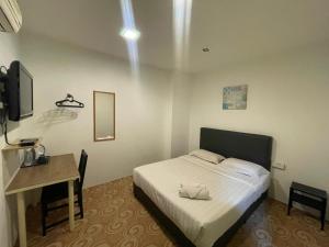 a bedroom with a bed and a desk and a television at HL HOTEL Kota Bharu in Kota Bharu