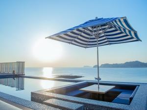 KotsuboTHE HARBOR TERRACE的一张桌子,旁边是一把遮阳伞