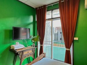 a green room with a television and a window at Dream Garden Villa Hotel Night Bazaar ChiangMai in Chiang Mai