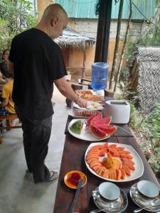 a man standing at a table with plates of food at Riverston Du Eco Cottage in Rattota
