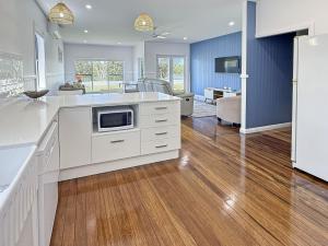 a kitchen with white cabinets and a living room at Googley's Cottage in Dunbogan