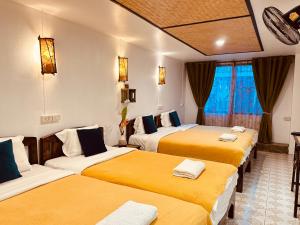 a room with three beds with yellow and white sheets at Dream Garden Villa Hotel Night Bazaar ChiangMai in Chiang Mai